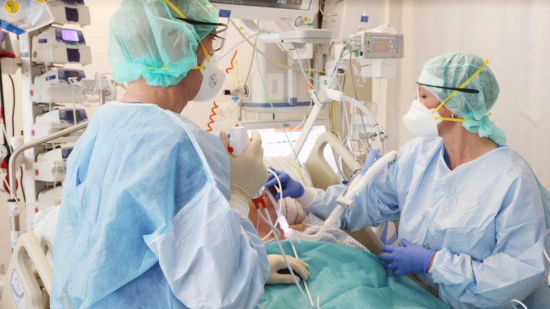 Zwei Krankenhausmitarbeiter versorgen einen Corona-Patienten.