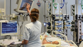 Eine Krankenschwester steht am Bett eines Patienten