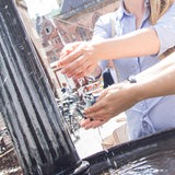 Zwei Frauen waschen sich an einem öffentlichen Brunnen in der Bremer Innenstadt die Hände.