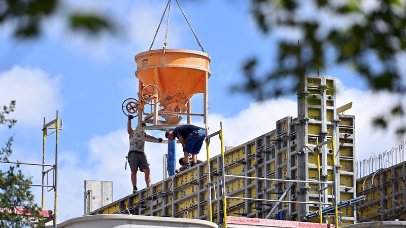 Bauarbeiter entnehmen Beton aus einem Betonkübel