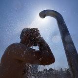 Ein Mann kühlt sich unter einer Dusche ab.