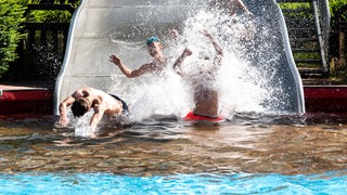 Schüler rutschen in ein Schwimmbecken.