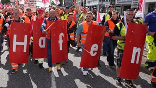 Hafen-Beschäftigte mit Verdi-Flaggen und einem aus einzelnen Plakaten gebildeten Schriftzug "Hafen" demonstrieren in der Hamburger Innenstadt.