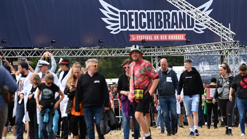 Besucher gehen über das Festivalgelände des Deichbrand Rockfestivals in Nordholz.