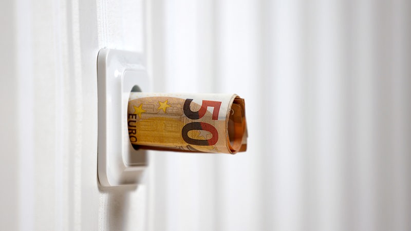 Ein 50-Euro-Schein wird in eine Steckdose geschoben