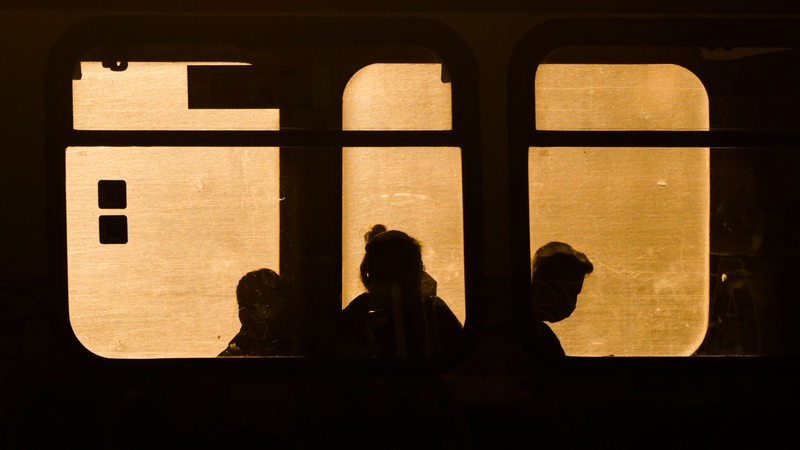 Fahrgäste sitzen am frühen Morgen bei Sonnenaufgang in einer Stadtbahn in der Region Hannover. 