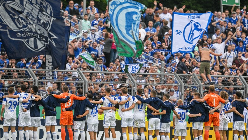 Die Schalker Mannschaft steht aufgereiht Arm in Arm vor der Fan-Kurve nach dem Pokalspiel gegen den Bremer SV.