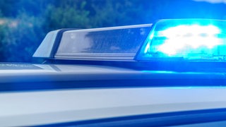 Das Blaulicht eines Polizeiwagens leuchtet auf.