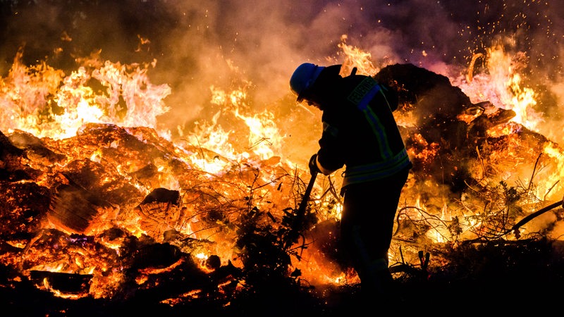 Ein Feuerwehrmann schichtet ein Osterfeuer auf.