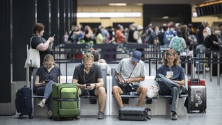 Menschen warten am Flughafen auf ihren Abflug in die Ferien.