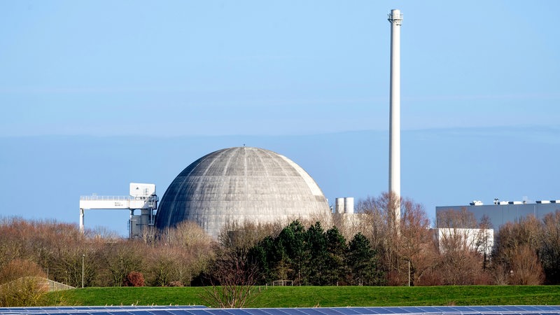 Das Kernkraftwerk Unterweser steht hinter Photovoltaikanlagen eines Solarparks. 