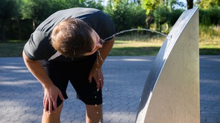 Ein Sportler trinkt Wasser an einem öffentlichen Trinkwasserspender