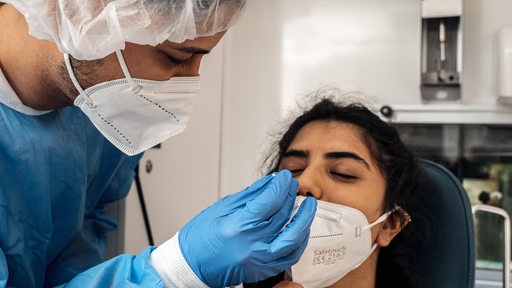 Ein Krankenpfleger nimmt einen Nasenabstrich bei einer Patientin