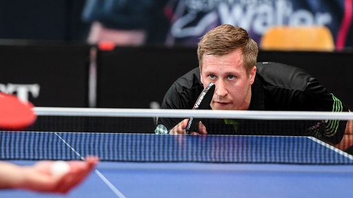 Werders Tischtennis-Profi Mattias Falck lauert auf den Aufschlag seines Gegners in gebückter Haltung am Tisch.