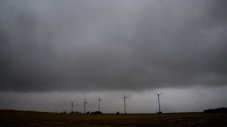 Eine Gewitterfront mit Starkregen zieht über Windräder hinweg.
