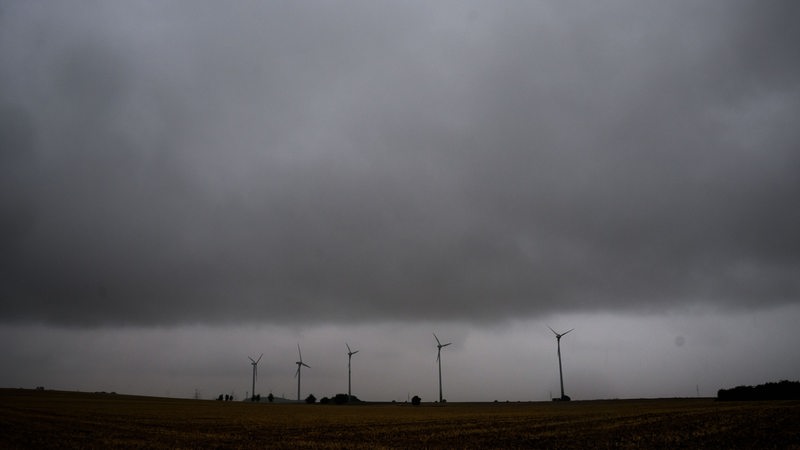 Eine Gewitterfront mit Starkregen zieht über Windräder hinweg.