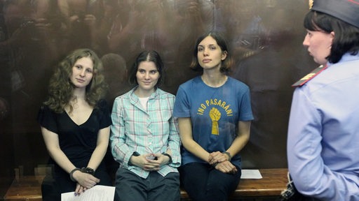 In einem gläsernen Kasten sitzen die angeklagte russische Frauen-Punk-Band "Pussy Riot" (Maria Aljochina, Jekaterina Samuzewitsch und Nadeschda Tolokonnikowa)