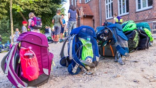 Schulranzen stehen auf einem Schulhof. 