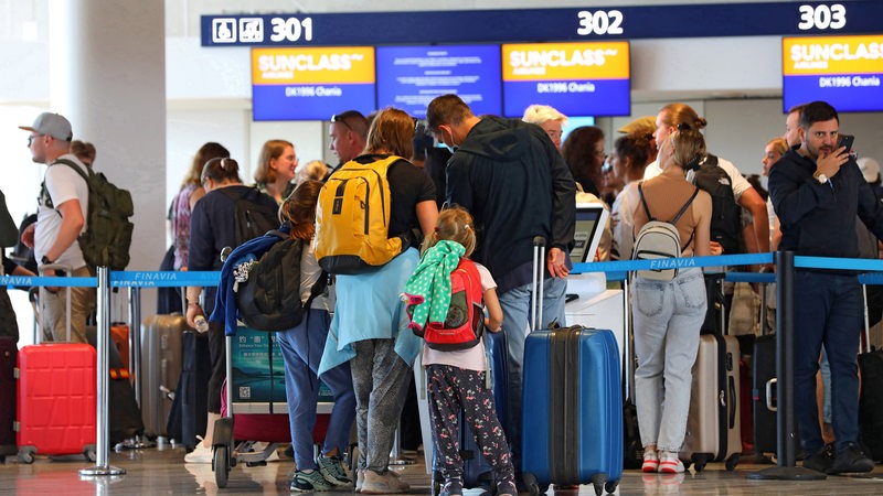 Menschen stehen vor ihrer Reise am Check-in-Schalter.