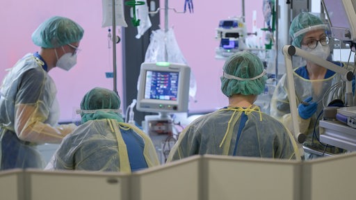 Pflegerinnen und Pfleger sowie eine Ärztin kümmern sich auf der Intensivstation für Corona-Patienten am Sana Klinikum Offenbach um einen Patienten. 