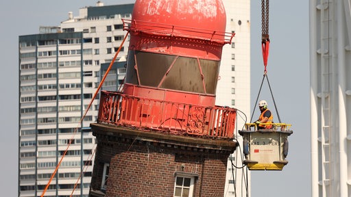 Von einer Krangondel aus wird am schiefen Leuchtturm auf der Mole in Bremerhaven die Demontage der Kuppel vorbereitet.