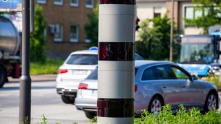 Nahaufnahme einer Radarfalle mit vorbeifahrenden Autos