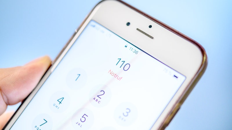 Ein Mann wählt die Notrufnummer 110 auf einem Smartphone.