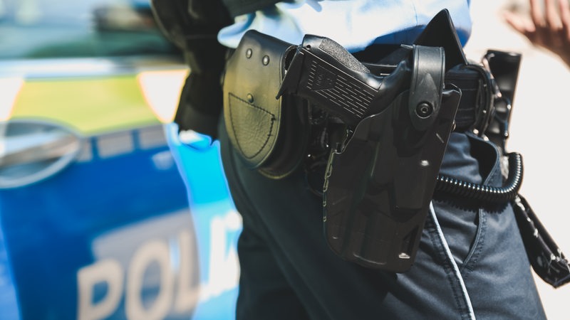 Ein Polizist steht vor einem Polizeiauto.