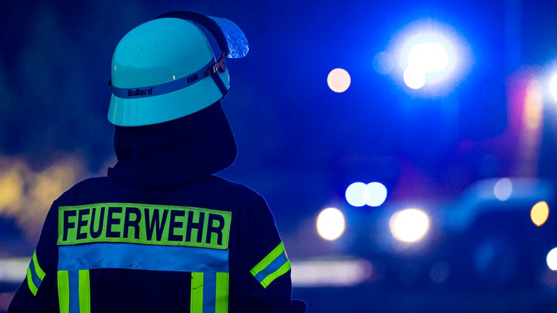 Ein Feuerwehrmann steht vor einem Feuerwehrfahrzeug.