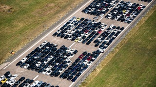 Luftaufnahme von vielen Mercedes-Fahrzeugen, die auf einer Landebahn parken. 