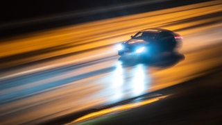 Ein Fahrzeug rast abends über die regennasse Autobahn A661 in Frankfurt am Main.