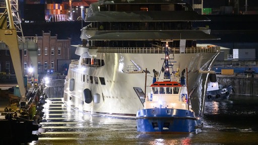 Die Luxusjacht Dilbar wird von Schleppern aus dem gefluteten Trockendock der Werft Blohm + Voss auf die Elbe vor den Landungsbrücken gezogen. 