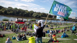 Ein junger Mann hält bei der Demonstration im Rahmen des internationalen Klimaprotesttages der Klimaschutzbewegung Fridays for Future eine Fahne mit der Aufschrift "Klima Retten Jetzt!".