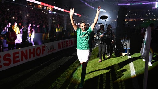 Claudio Pizarro läuft mit hochgereckten Armen im dunklen Weser-Stadion im Scheinwerferlicht seine Ehrenrunde zum Abschied.