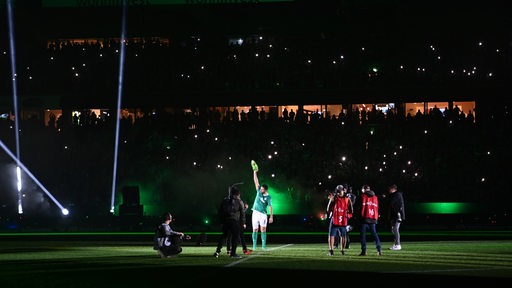Claudio Pizarro reckt im Scheinwerferlicht auf dem Spielfeld seine Fußball-Schuhe in die Höhe.