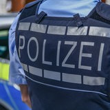 Polizist steht mit Rücken zur Kamera vor Polizeiauto