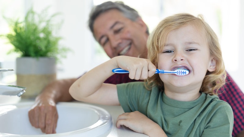 Ein Junge putzt sich mit seinem Opa die Zähne