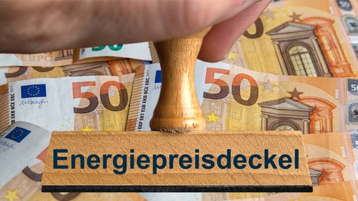 Ein Stempel mit der Aufschrift "Energiepreisdeckel" vor Geldscheinen