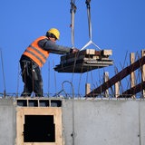 Ein Bauarbeiter arbeitet auf dem Dach eines Rohbaus