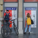 Zwei Personen stehen vor Fahrkartenautomaten.
