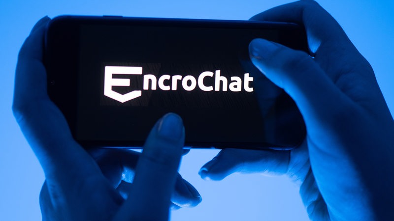 Eine Frau hält ein Smartphone mit dem Logo des Krypto-Messengerdienstes Encrochat (gestellte Szene).