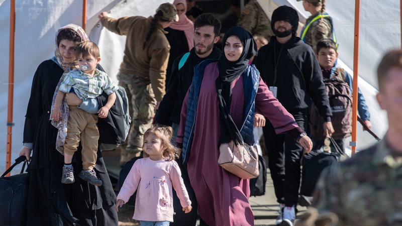 Flüchtlinge aus Afghanistan tragen Kinder und Koffer.
