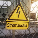 Schild an einem Zaun mit der Aufschrift Stromausfall