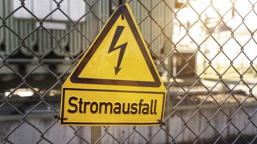 Schild an einem Zaun mit der Aufschrift Stromausfall