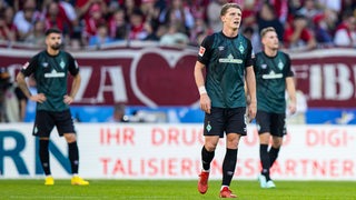Die Werder-Spieler Anthony Jung, Jens Stage und Marvin Ducksch stehen tief frustriert auf dem Spielfeld nach der Niederlage in Freiburg.
