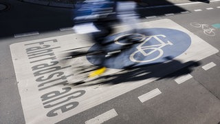 Ein Radfahrer fährt über ein Fahrradschild auf einer Straße.