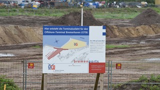 Ein Schild weist am in Bremerhaven auf den geplanten Bau eines Offshore-Terminals hin.