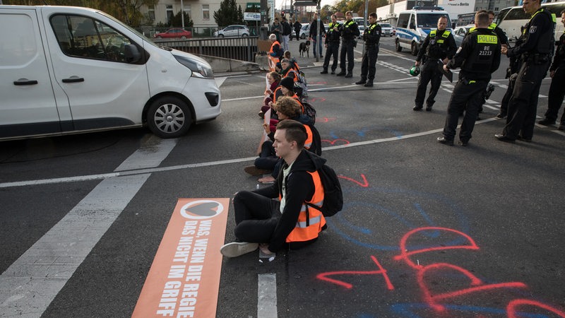 Klimaaktivisten blockieren in Berlin eine Straße.