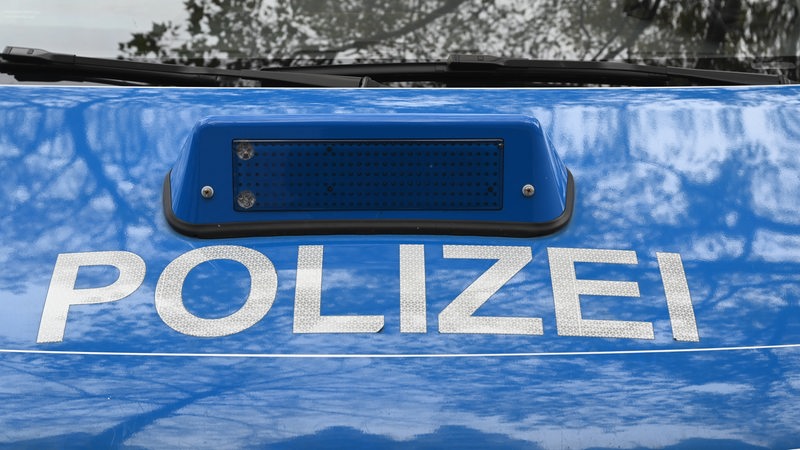 Auf der Motorhaube eines Polizeiautos steht die Aufschrift "Polizei".
