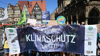 Teilnehmer einer Großdemonstration für Klimaschutz halten ein Plakat hoch